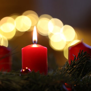 Eine Kerze brennt am ersten Advent an einem Adventskranz.