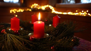Eine Kerze brennt am ersten Advent an einem Adventskranz.