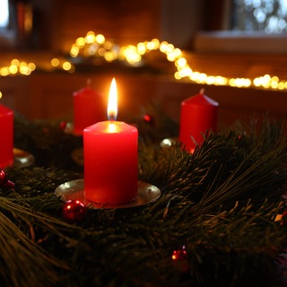 Eine Kerze brennt am ersten Advent an einem Adventskranz.