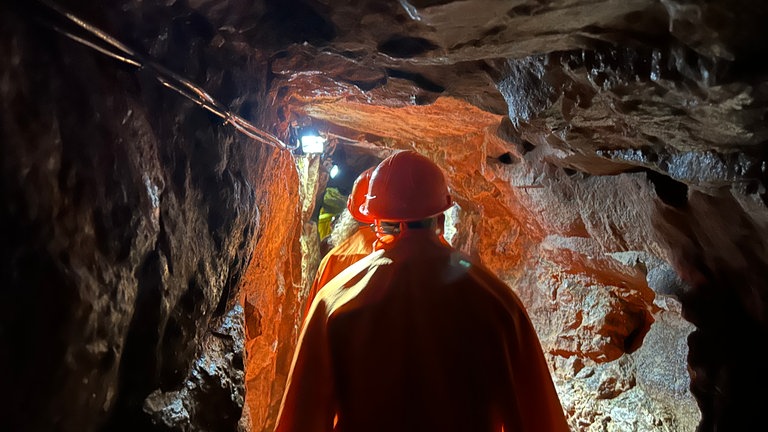 Der perfekte Tag mit SWR1 im Nordschwarzwald. Eine Gruppe von Menschen mit orangenen Helmen geht durch einen engen Gang eines Bergwerkstollens.