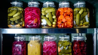 Viele Gläser mit eingemachten Gemüse und Obst stehen in einerm Regal.