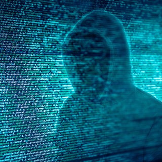 Sicherheit und Schutz im Cyberspace - wie wehre ich mich gegen Hacker, Betrüger und Spammer, gegen Scammer, Idenditätsdiebstahl und Pädophile? Wir zeigen Euch, wie Ihr Euch und Eure Kinder vor Gefahren im Internet schützen könnt - nicht nur am Safer Internet Day! Das Symbolbild zeigt einen Hacker, dessen Gesicht von einer Hoody-Kapuze versteckt wird, im Hintergrund grünlich-blauer Computercode.