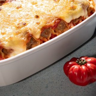 In einer weißen Auflaufform sind Cannelloni mit Merguez-Würsten als Auflauf angerichtet. 