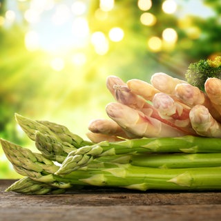Grüner und weißer Spargel liegt auf einem Holzbrett.