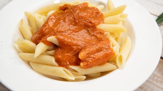 Auf einem Teller angerichtet: Pasta mit einer Tomaten-Paprika-Sauce und Mozzarella