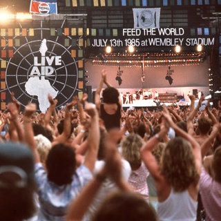 Vor 40 Jahren: Die Fans jubeln während des Live Aid Auftritts von Queen-Sänger Freddie Mercury.  | 40 Jahre Live Aid: Das größte Rockkonzert der Geschichte