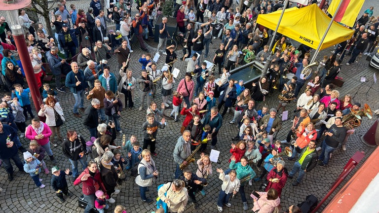 Marktplatz in Triberg steht voller Leute, die Instrumente in der Hand haben.
