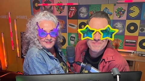 Annett Lorisz und Jochen Stöckle tragen während der Hitparade 2025 bunte Sonnenbrillen.