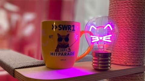 SWR1 Hitparade-Tasse und eine Glühbirne, die leuchtet wie ein Katzengesicht
