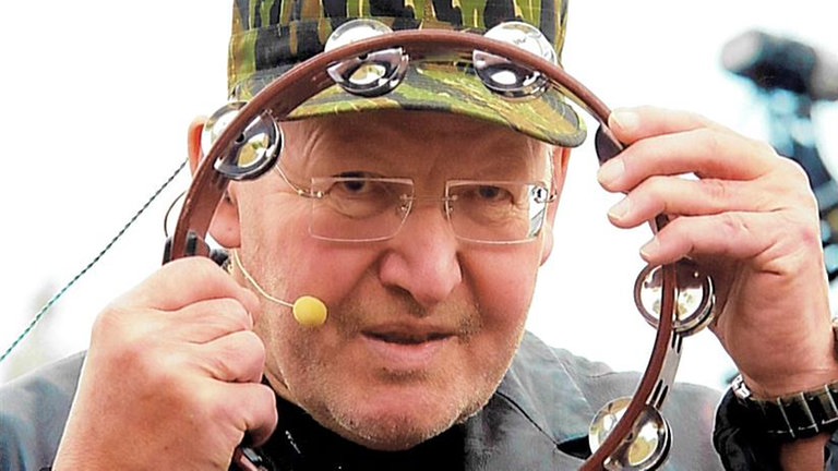 Matthias Holtmann hält einen Schellenkranz vor sein Gesicht und schaut durch.