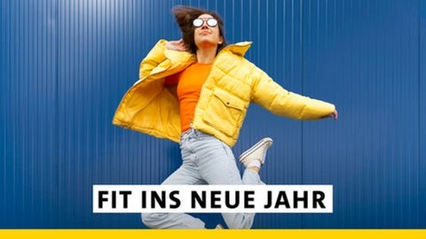 Eine junge Frau mit gelber Winterjacke und Jeans springt vor einem blauen Hintergrund in die Luft. Startet fit ins neue Jahr mit SWR1! Mit gesunden Rezepten, und den besten Fitness-Tipps.