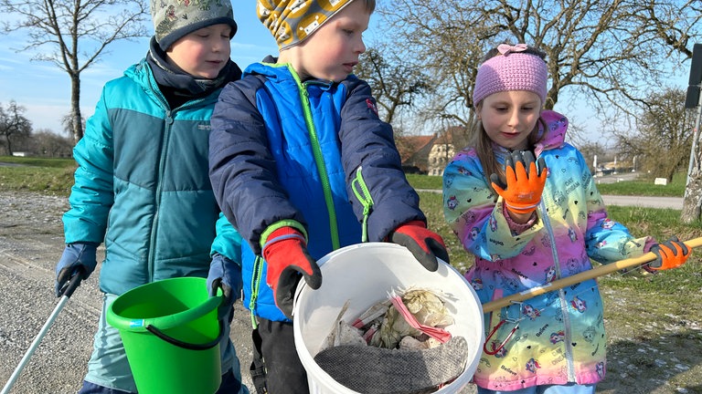 Jannis, Jannis und Amelia von der Kindergartengruppe zeigen, welchen Müll sie gesammelt haben bei der Dreck weg-Woche in Langenburg.