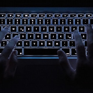 Ein Mann benutzt die beleuchtete Tastatur eines Notebooks