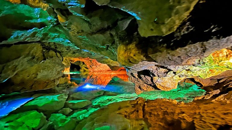 Blick in die mystische Wimsener Höhle. Das klare Wasser wird durch Scheinwerfer beleuchtet.