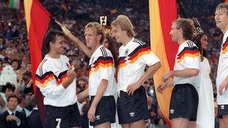Die deutschen Spieler (v.l.) Pierre Littbarski, Andreas Brehme, Jürgen Klinsmann, Rudi Völler und Guido Buchwald erwarten am 8.7.1990 im Olympiastadion von Rom vor ihrer Landesfahne stehend die Siegerehrung der Fußball-Weltmeisterschaft.