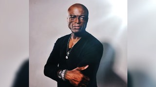 Seal steht mit verschränkten Armen da.