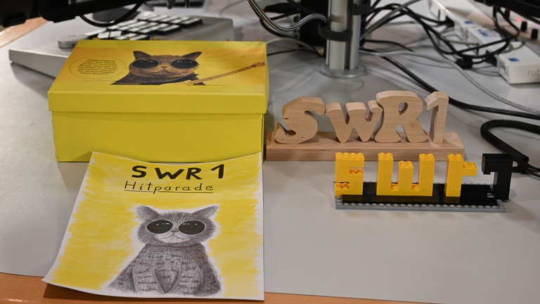 ... dabei bleibt es aber nicht. Mittlerweile haben uns unsere Hörerinnen und Hörer eine Hitcat-Kiste, ein selbstgemaltes Hitcat-Plakat, einen geschnitzten SWR1 Schriftzug und einen aus Lego vorbeigebracht.