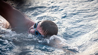 Extremschwimmer André Wiersig taucht aus den Wellen zum Atmen auf.