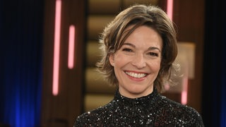 Anna Planken, Moderatorin, lächelt in die Kamera.