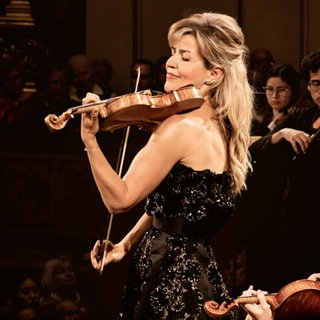 Anne-Sophie Mutter, Stargeigerin, steht zwischen anderen Streichern und spielt Geige.