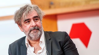 Deniz Yücel, Journalist, blickt zu einem Gesprächspartner.