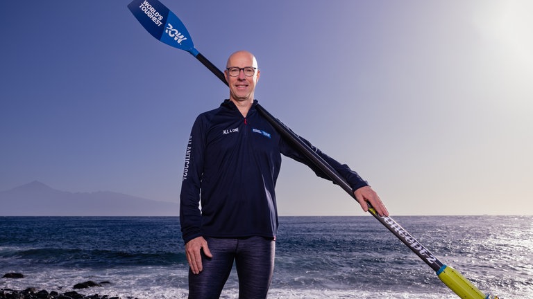 Extremsportler Martin Stengele hält sein Doppelruder über der Schulter, im Hintergrund der Atlantik