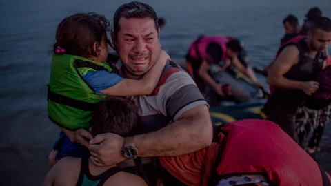Laith Majid al Amiri cries as he holds his youngest children as they arrived on the Greek island of Kos. 