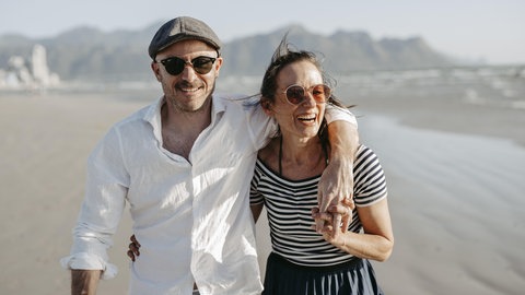 Ein glückliches Paar am Strand. Symbolbild für gelingende Liebe und Beziehungen. Für eine stabile Bindung ist Sex sehr wichtig, sagt Paarberater Christian Thiel.