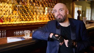 Ingmar Stadelmann, Comedian, lehnt mit seinem rechten Arm an einer Theke. Bei seinen Gags nimmt Comedian Ingmar Stadelmann selten Rücksicht auf Gefühle anderer. Jetzt geht er mit der AfD auf Konfrontationskurs: Sein neues Programm heißt "Stadelmann liest Höcke".