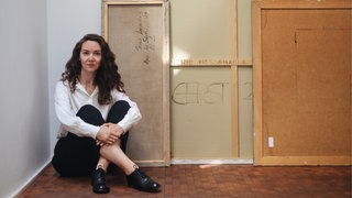 Schriftstellerin Iris Wolff sitzt auf dem Boden und schaut in die Kamera.
