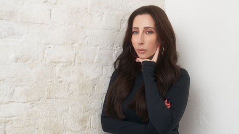 Marina Buzunashvilli, Head of PR bei Sony Music, lehnt mit der rechten Schulter an einer Wand und hat die linke Hand unter ihrem Kinn.