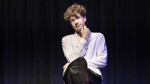 Mentalist und Mentalmagier Timon Krause sitzt mit verschränkten Beinen und seiner Hand am Kinn auf einem Stuhl. Er liest Gedanken und unsere Körpersprache. Warum er weiß, was in uns vorgeht, verrät er in SWR1 Leute.