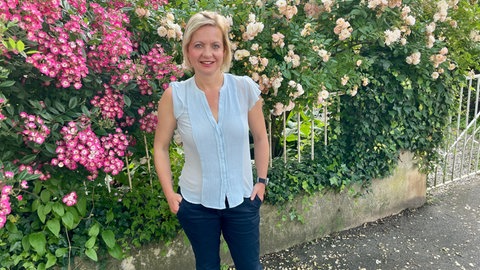 Die Direktorin des St. Josefskrankenhaus in Freiburg, Dr. Michaela Bossart, steht vor blühenden Büschen.