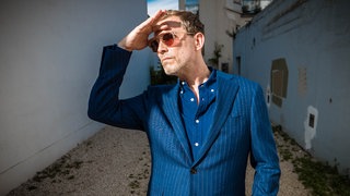 Musiker Timo Blunck steht seitlich zur Kamera und trägt eine Sonnenbrille. In SWR1 Leute spricht Timo Blunck über Palais Schaumburg und Sex in den 80ern.
