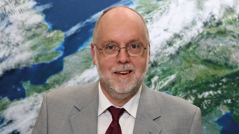 Prof. Roland Potthast, beim Deutschen Wetterdienst, steht vor einer Wetterkarte. Er arbeitet für den Deutschen Wetterdienst. In SWR1 Leute erklärt er, wie das Wetter vorhergesagt wird und welche Chancen er für die Wetterprognose mit KI sieht.