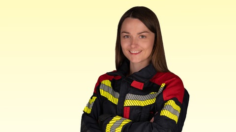 Rettungssanitäterin Ronja Ester lächelt mit verschränkten Armen in die Kamera.