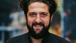 Soziologe Prof. Dr. Aladin El-Mafaalani schaut fröhlich in die Kamera. | So entscheidet Herkunft über Bildungschancen