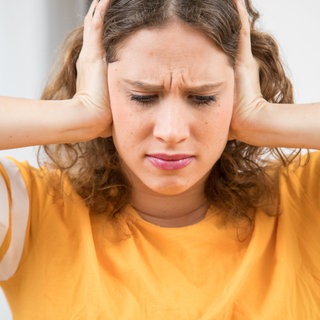 Eine junge Frau hält sich die Ohren zu mit schmerzverzerrtem Gesicht. Hilfe bei chronischem Tinnitus oder Schwindel und Übungen zur Vagusnerv-Stimulation: HNO-Arzt und Tinnitus-Spezialist Uso Walter gibt in SWR1 Leute Tipps zur Selbsthilfe.