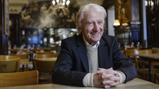 Der Schweizer Kabarettist Emil Steinberger sitzt im Restaurant an einem Tisch. Spätestens seit den 70er Jahren gehört Emil Steinberger fest zur Spitze des deutschsprachigen Kabaretts. Sein Humor und seine Sprache prägten Generationen. Legendär sein Sketch mit dem "Bömbli" und dem "Schäufeli" - und natürlich das berühmte "Ogtern". Er ist zu Gast in SWR1 Leute.