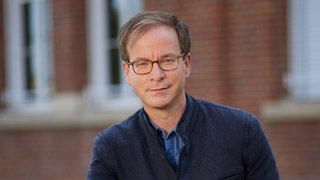 Unternehmer und Sterbebegleiter Markus Müller schaut freundlich in die Kamera. | Vom Top-Manager zum Sterbebegleiter | SWR1 Leute