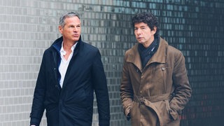 Virologe Christian Drosten und Journalist Georg Mascolo schreiten nebeneinander her.