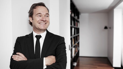 Unternehmensberater Frank Dopheide hat die Arme überschränkt und lächelt.  Warum werden Freigeister und Kreative oft übersehen? Wie kann man Andersartigkeit als Wettbewerbsvorteil nutzen? Das sind Fragen, mit denen sich Frank Dopheide beschäftigt. Er gründete eine Agentur, die die Kraft der Persönlichkeit und Kreativität in den Mittelpunkt stellen will. 