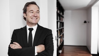 Unternehmensberater Frank Dopheide hat die Arme überschränkt und lächelt.  Warum werden Freigeister und Kreative oft übersehen? Wie kann man Andersartigkeit als Wettbewerbsvorteil nutzen? Das sind Fragen, mit denen sich Frank Dopheide beschäftigt. Er gründete eine Agentur, die die Kraft der Persönlichkeit und Kreativität in den Mittelpunkt stellen will. 