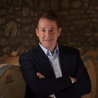 Winzer und Krimi-Autor Andreas Wagner steht mir verschränkten Armen vor Weinfässern im Weinkeller. | SWR1 Leute