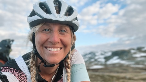 Abenteurerin Jasmin Böhm trägt einen Helm und lacht in die Kamera.