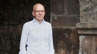 Prof. Heinz Bude steht vor einer alten Mauer.