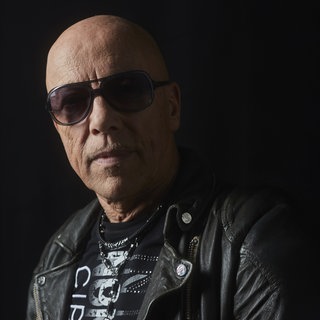 Musiker Toni Krahl blickt vor schwarzen Hintergrund in die Kamera.