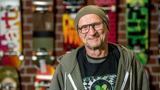 Titus Dittmann lächelt in die Kamera. Das Skateboard hat das Leben von Titus Dittmann komplett verändert: Der ehemalige Lehrer wurde zum Wegbereiter eines neues Sports. Mit seiner Organisation "skate-aid" baut er mittlerweile weltweit Skateparks für Kinder. In SWR1 Leute erzählt er, wie aus dem vermeintlich kurzfristigen Trend eine Bewegung wurde.