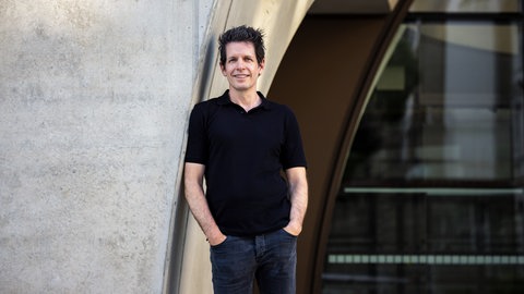 Martin Andree, Medienwissenschaftler, lehnt mit der Schulter an einer Betonwand.