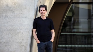 Martin Andree, Medienwissenschaftler, lehnt mit der Schulter an einer Betonwand.